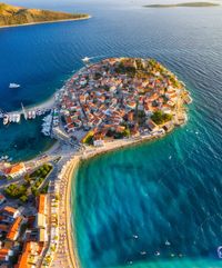 Primosten town, Croatia. View of the city from the air. Seascape with beach and old town. View from drone on the peninsula with houses. Landscape during sunset.